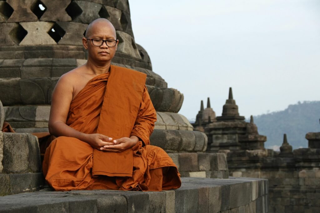 A bald Buddhist monk meditates at a historic temple, embodying spirituality and peace.