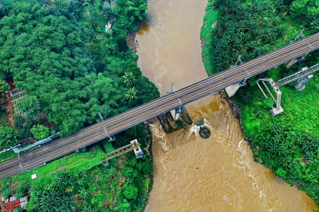 Aerial view of a railway bridge crossing a lush river in Sindang Jaya, Indonesia.
