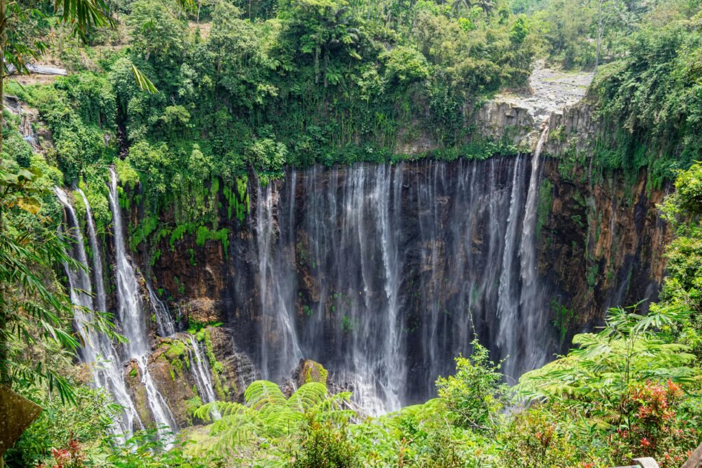 Tumpak Sewu Waterfall cascading through green forest in East Java, Indonesia.