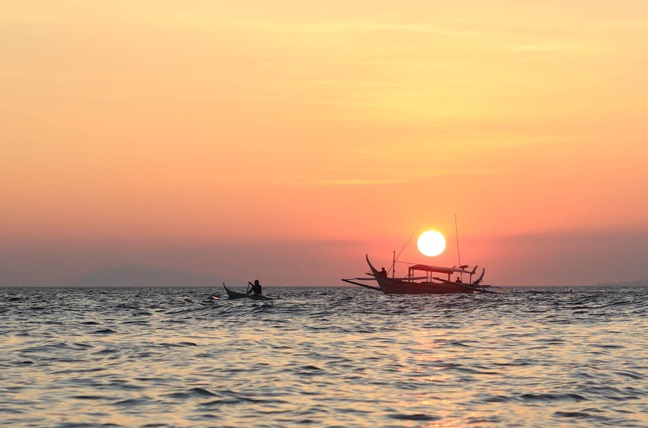 Beautiful sunset over the ocean with a silhouetted boat adding tranquility to the scenic view.